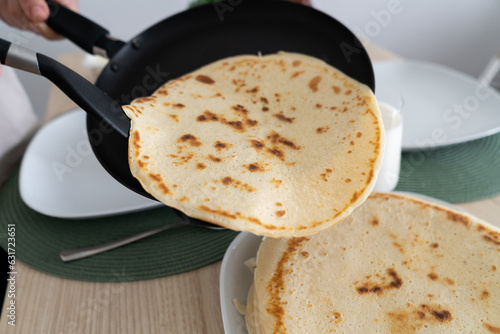 Slika na platnu Placing pancakes on a plate after frying them in a pan