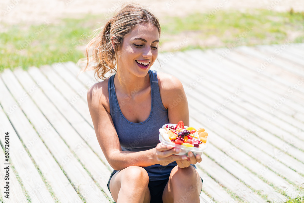 Young pretty sport woman holding a bowl of fruit at outdoors with happy expression Young pretty sport woman holding a bowl of fruit at outdoors with happy expression
