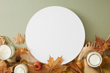 Enchanting fall aesthetic concept. Top view photo of candles, warm cashmere plaid, acorns, pumpkins, maple leaves on olive background with blank circle for promo or message