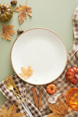 Heartwarming thanksgiving gathering idea. Top view photo of plate, cutlery, glass, tablecloth, autumnal decorations on olive background