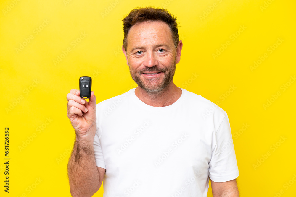 Middle age caucasian man holding car keys isolated on yellow background smiling a lot Middle age caucasian man holding car keys isolated on yellow background smiling a lot