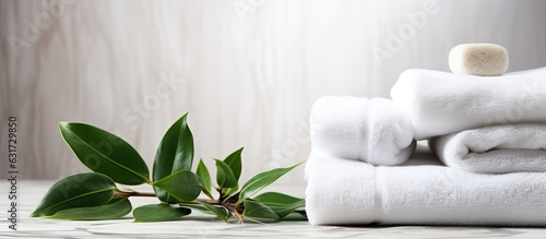 a marble background with white stones, a towel, and green plant leaves, creating a space for body care and beauty treatment. It is associated with spas, wellness centers, and beauty salons, providing