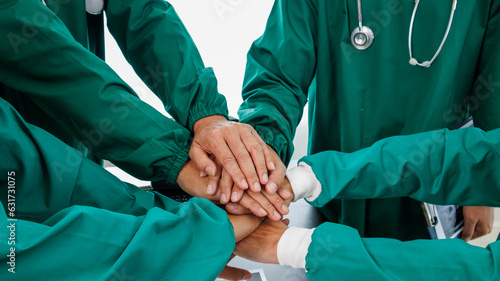 Multiracial medical team having a meeting with doctors in white lab coats and surgical scrubs seated at a table discussing a patients records