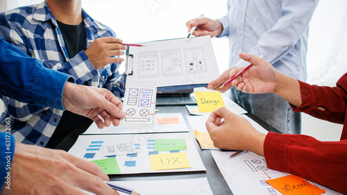 Close-up ux developers and ui designers use augmented reality to brainstorm on mobile app interface wireframe designs on modern office desks. Creative digital development office