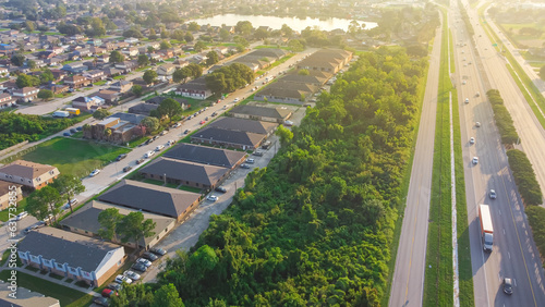 Busy traffic on Interstate 10 highway near Lake Barrington early morning along row of townhouses, condos, lush green trees and residential units in Little Woods, Eastern New Orleans photo