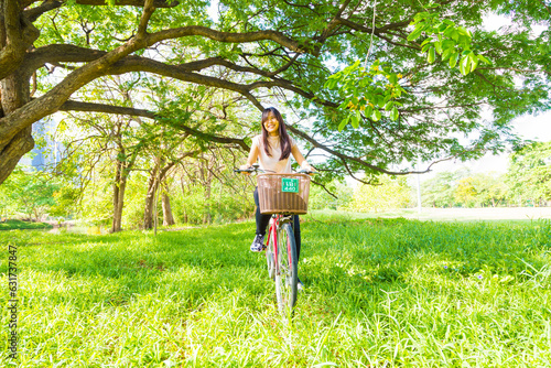 Beautiful asian woman with bicycle on green meadow tree park