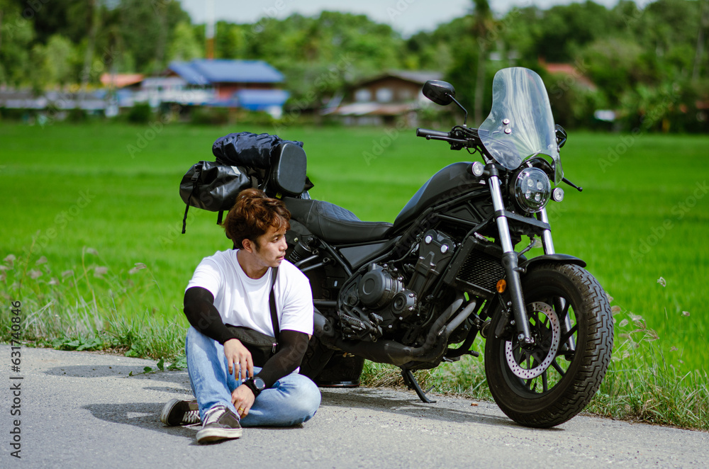 Fototapeta premium asian young man is sitting on road with cruiser motorcycle and g