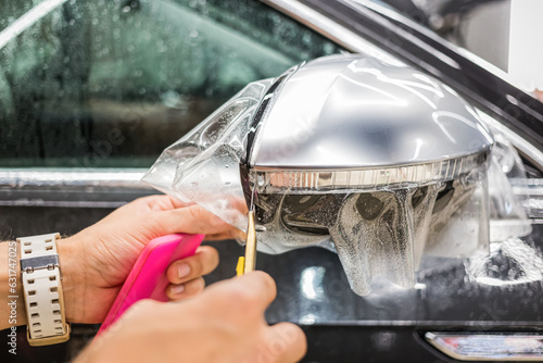 The process of installing PPF on the side mirror. Car wrapping close-up.