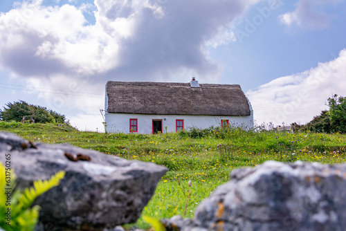 Old traditional irish cottage with a stone fence on a bright sunny day with a cloudy sky
