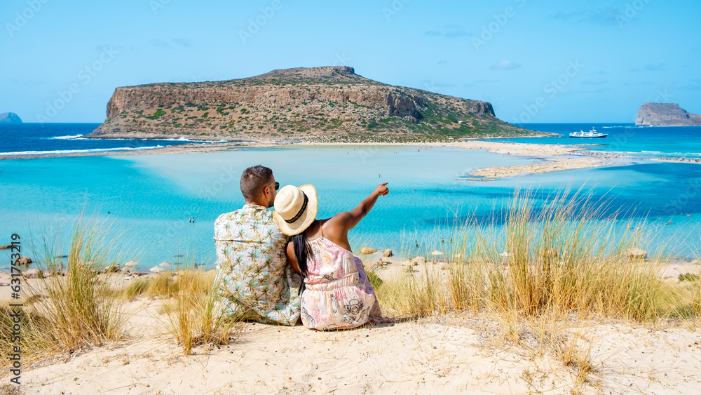 Obraz premium Crete Greece, Balos lagoon Crete island, Greece. Tourists relax at the crystal clear ocean of Balos Beach. a couple of men and a woman visit the beach during a vacation in Greece on a sunny day