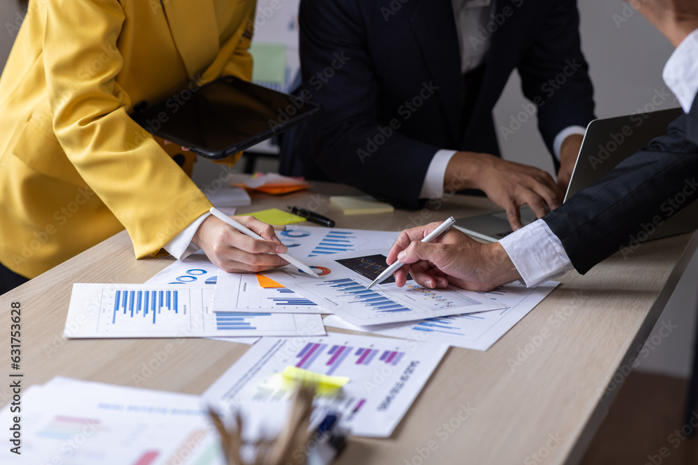 Group of confident business people point to graphs and charts to analyze market data, balance sheet, account, net profit to plan new sales strategies to increase production capacity.	