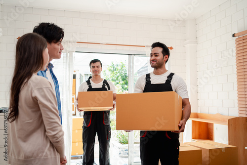 Asian Couple check while unloading boxes and furniture from a pickup truck to a new house with service cargo two men movers worker in uniform lifting boxes. concept of Home moving and delivery. © Kiattisak