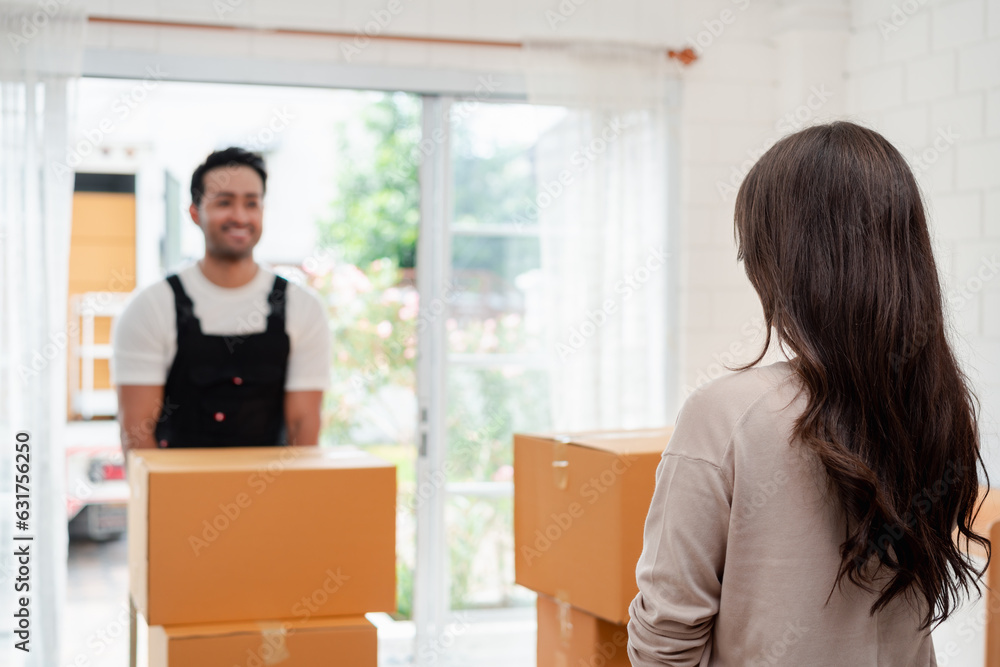 Woman check while unloading boxes and furniture from a pickup truck to a new house with service cargo two men movers worker in uniform lifting boxes. concept of Home moving and delivery. Woman check while unloading boxes and furniture from a pickup truck to a new house with service cargo two men movers worker in uniform lifting boxes. concept of Home moving and delivery.