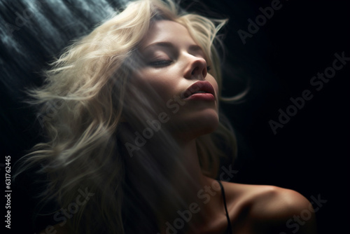 Blonde woman with dark background basking in the light with eyes close