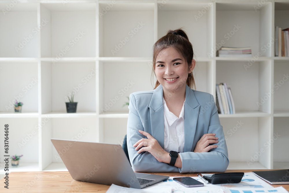 Young beautiful Asian businesswoman crossing her arms together while sitting in her office room. Young beautiful Asian businesswoman crossing her arms together while sitting in her office room.