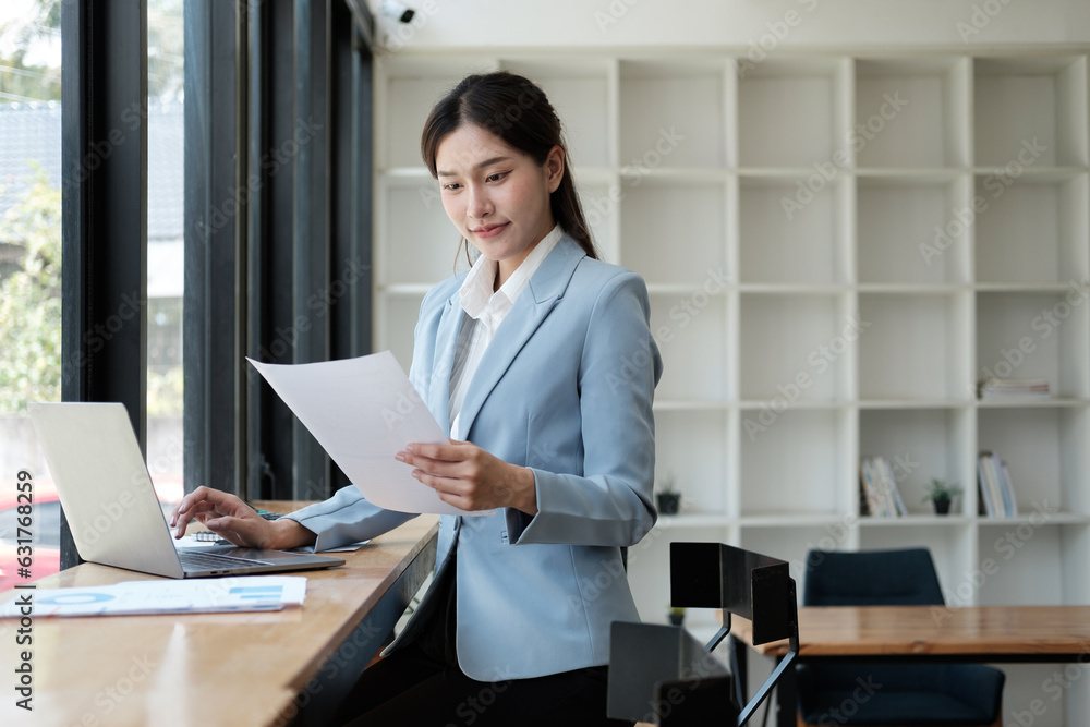 Smart and pretty young Asian businesswoman holding paper, analyzing information from the document, preparing for the next project. Smart and pretty young Asian businesswoman holding paper, analyzing information from the document, preparing for the next project.
