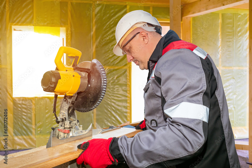 Man joiner. Stationary circular saw. Carpenter saws wooden board. Joiner at work. Man uses circular saw. Equipment for woodworking. Joiner in gray uniform. Construction worker sawing parquet Man joiner. Stationary circular saw. Carpenter saws wooden board. Joiner at work. Man uses circular saw. Equipment for woodworking. Joiner in gray uniform. Construction worker sawing parquet
