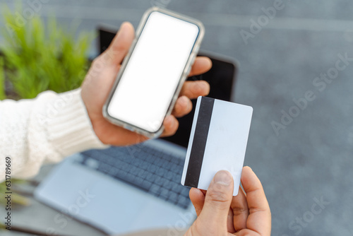 Close up of business man hand holding credit card using mobile phone shopping online, selective focus. Mockup. Technology concept © Maria Vitkovska