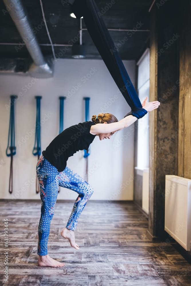 Woman practices aerial yoga pose in hammock Woman practices aerial yoga pose in hammock