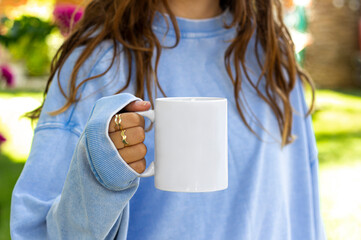 Girl is holding white mug in hands. Blank 11 oz ceramic cup. mug mockup with copy space