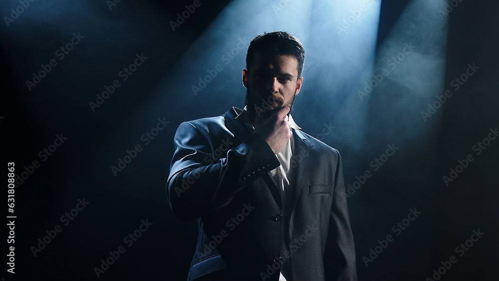 Portrait of a bearded man sitting with a serious face, against a dark background. Portrait of a bearded man sitting with a serious face, against a dark background.