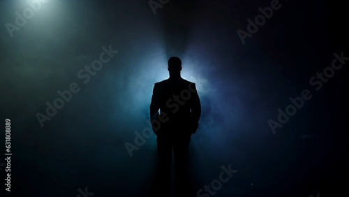 Portrait of a bearded man sitting with a serious face, against a dark background.