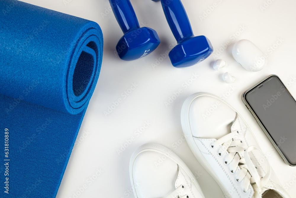 The concept of sports accessories. Photo of white sneakers, blue dumbbells The concept of sports accessories. Photo of white sneakers, blue dumbbells