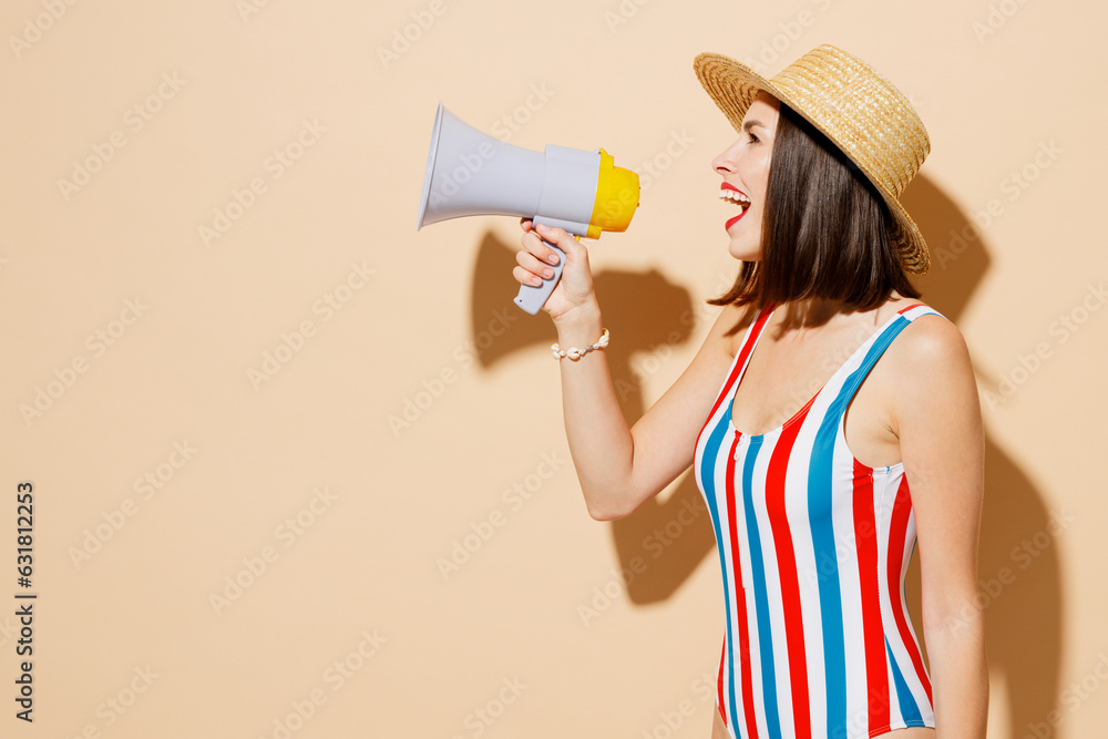 Side view young woman wears one-piece swimsuit straw hat near hotel pool scream shout in megaphone announce sale Hurry up isolated on plain beige background Summer vacation sea rest sun tan concept.