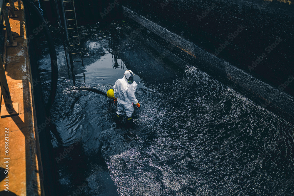 Fototapeta premium Male worker cleaning sump crude oil surface background