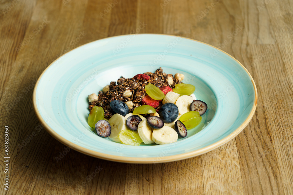 A bowl of cereal with fruits on a wooden table A bowl of cereal with fruits on a wooden table