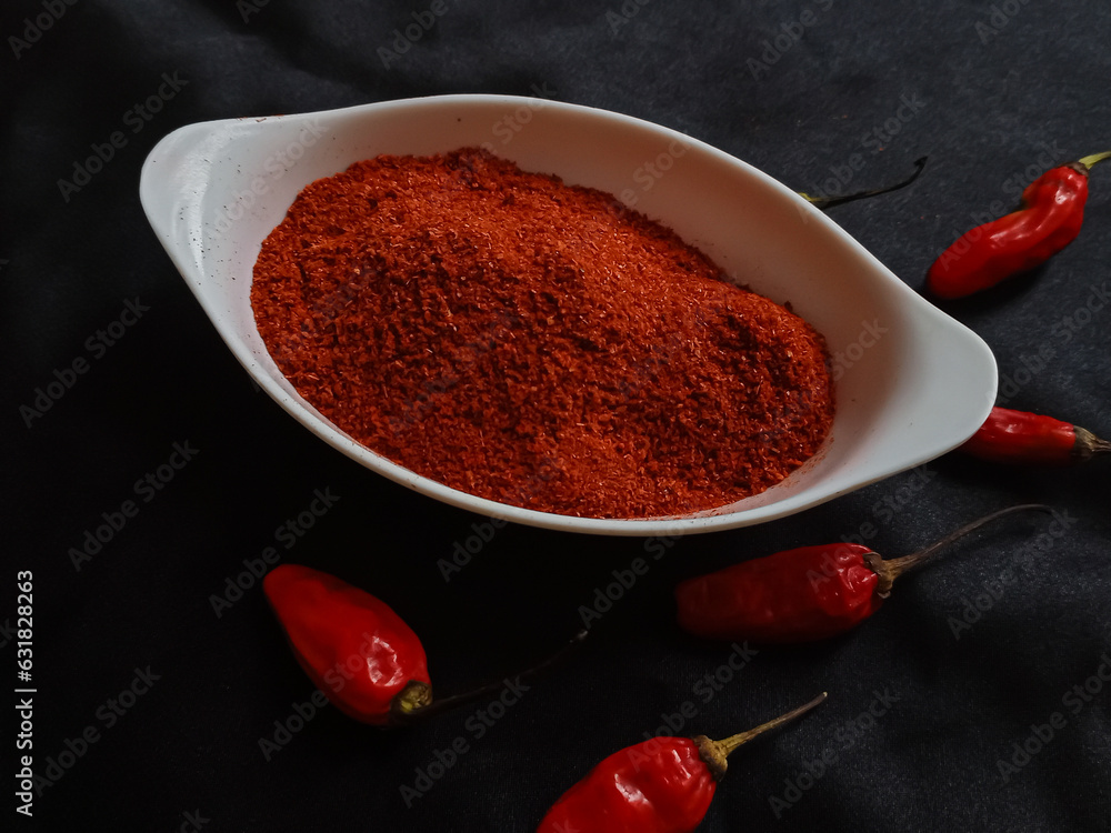 Φωτογραφία Chili powder is a seasoning blend of ground chiles in a white bowl with red chiles on a black background