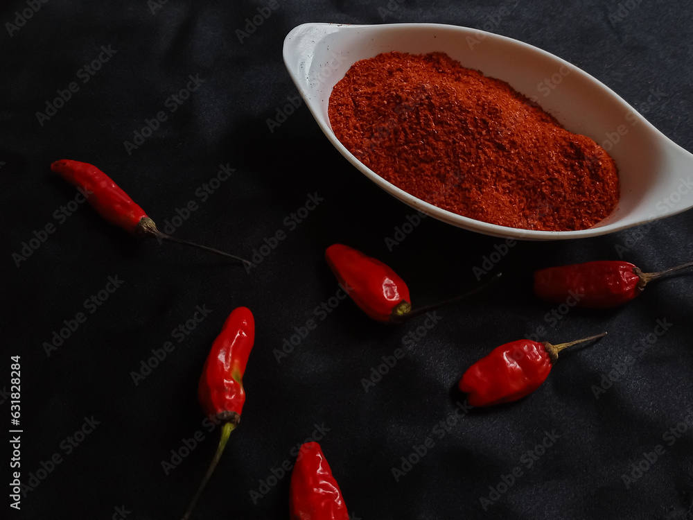 Φωτογραφία Chili powder is a seasoning blend of ground chiles in a white bowl with red chiles on a black background