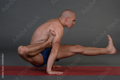 Man doing yoga in photo studio on isolated background. 