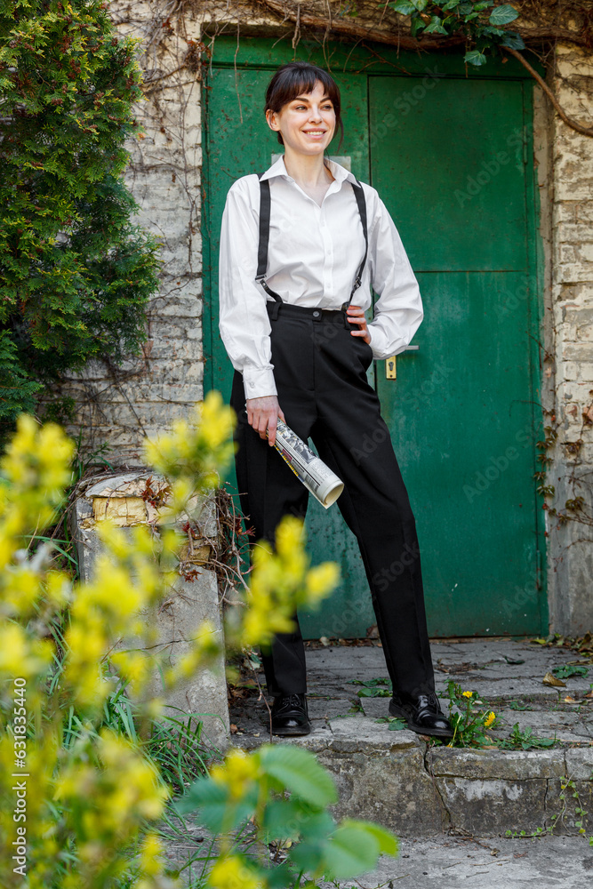 Beautiful girl with a newspaper in her hands, in a white shirt, in black trousers with suspenders Beautiful girl with a newspaper in her hands, in a white shirt, in black trousers with suspenders