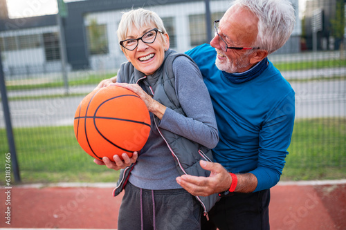 Cheerful active senior couple playing basketball on the urban basketball street court. Happy living after 60 © lordn