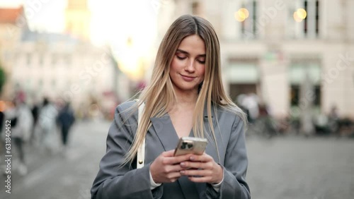 Wallpaper Mural Portrait of attractive blonde woman texting message on smartphone on city street Torontodigital.ca