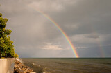 Rainbow over water. Landscape of lake Geneva, mountain, waves and double rainbows in the sky.
