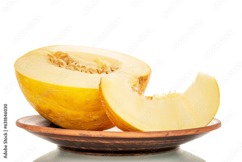 One half of a yellow melon and one slice on a clay plate, macro, isolated on white background.