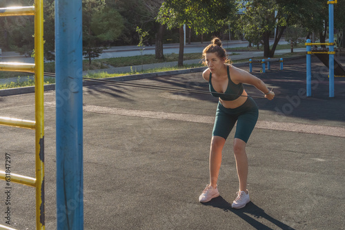 Young caucasian woman exercising with a rubber expander on a street sports ground