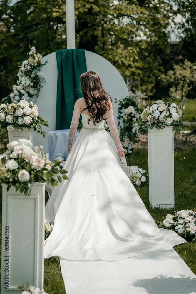 Beautiful bride posing in her wedding dress in a green park Beautiful bride posing in her wedding dress in a green park