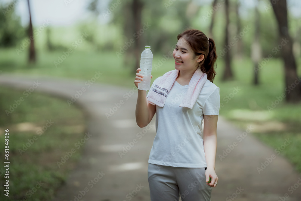 Young Asian woman holding water bottle during jogging in park, drinking clean water, healthy running Young Asian woman holding water bottle during jogging in park, drinking clean water, healthy running