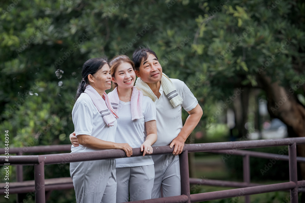 Beautiful Asian woman taking her father and mother to exercise in the park happily, with a smile. Young woman invites parents to exercise, warm family, good health. concept health care life insurance. Beautiful Asian woman taking her father and mother to exercise in the park happily, with a smile. Young woman invites parents to exercise, warm family, good health. concept health care life insurance.