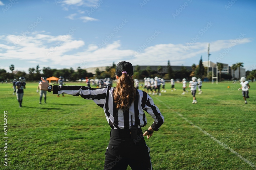Closeup of an American football referee standing on the field watching the game.