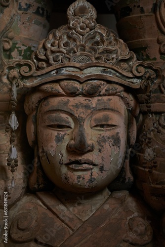Closeup shot of a large, ornate statue atop a rock pedestal at the entrance of Todaji Nara Temple