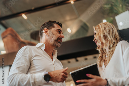 Smiling business colleagues discussing over digital tablet in office