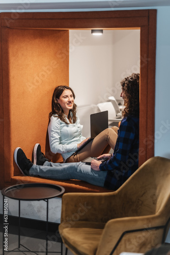 Lovely couple, coworkers, having a conversation and smiling while working together lying on a recessed wall area