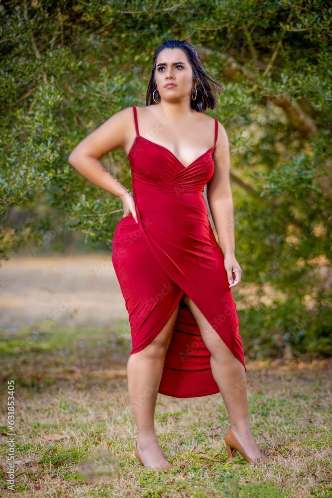 Beautiful Hispanic model posing in a red dress outdoors during sunrise Beautiful Hispanic model posing in a red dress outdoors during sunrise