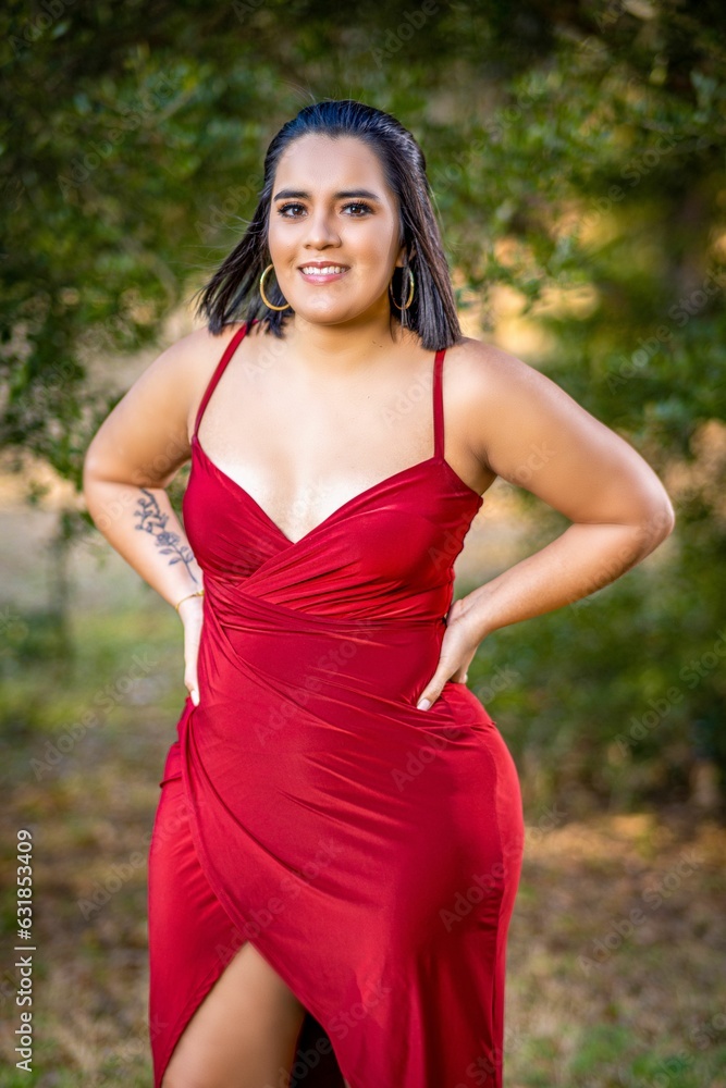 Vertical shot of a Hispanic model posing in a red dress outdoors Vertical shot of a Hispanic model posing in a red dress outdoors