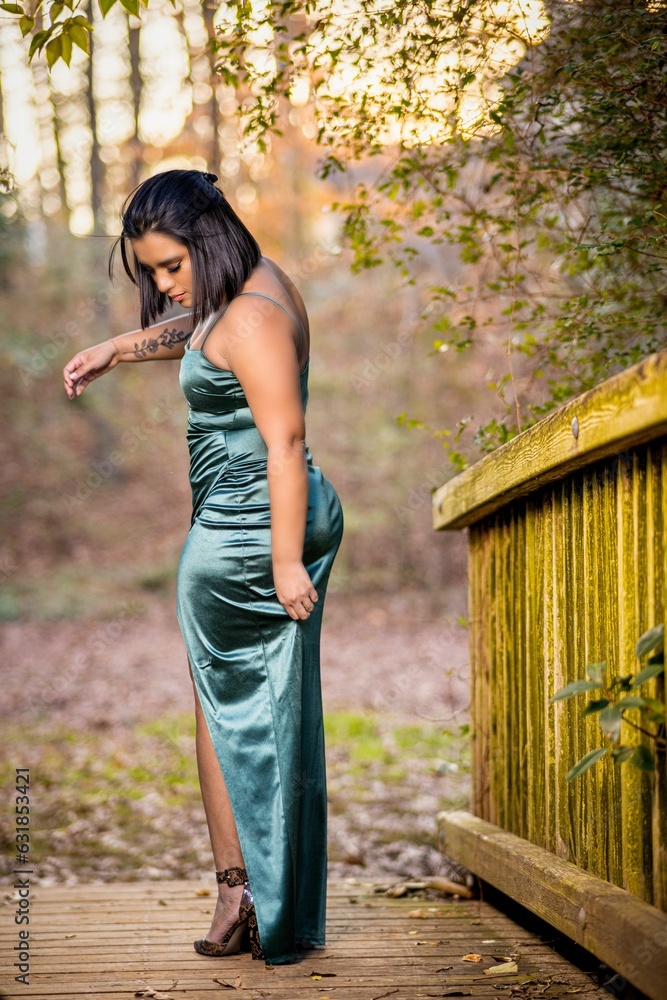 Naklejka premium Beautiful Hispanic model posing in a green dress outdoors during sunrise