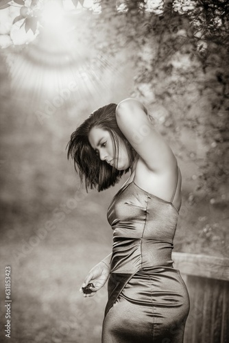 Vertical grayscale shot of a Hispanic model posing in a red dress outdoors